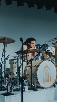 a man is playing drums in front of other drummer's instruments and drum sticks