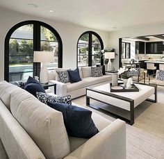 a living room filled with white couches and chairs next to an open floor plan