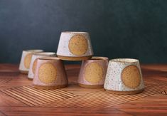 five ceramic cups sitting on top of a wooden table