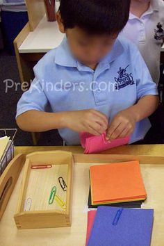 a young boy sitting at a desk with scissors and paper