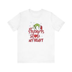 A cute and playful short sleeve tee featuring the design 'Grinch: My Students Stole My Heart'. Perfect for educators who want to show their love for teaching. This tee is great for casual wear and can be easily layered for different looks. Ideal for teachers to wear during holidays like Christmas or Teacher Appreciation Week. Product features - Made with 100% lightweight cotton for breathability - Retail fit for casual and semi-formal settings - Side seams for structural support - Ribbed knit collar with seam for shape retention - Tear-away label for minimal skin irritations Care instructions - Machine wash: cold (max 30C or 90F) - Non-chlorine: bleach as needed - Tumble dry: low heat - Iron, steam or dry: medium heat - Do not dryclean Educator Gifts, Grinch Shirts, Holiday Apparel, School Staff, Teacher Appreciation Week, Teacher Tshirts, Christmas Tees, T Shirt Funny, Funny Christmas