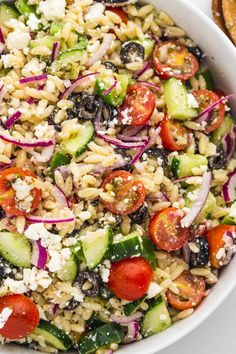 a salad with cucumbers, tomatoes, onions and feta cheese in a white bowl