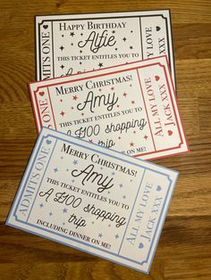 three tickets with merry christmas and happy new year written on them, sitting on a wooden table