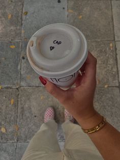 a person holding up a coffee cup with writing on the top and bottom half of it