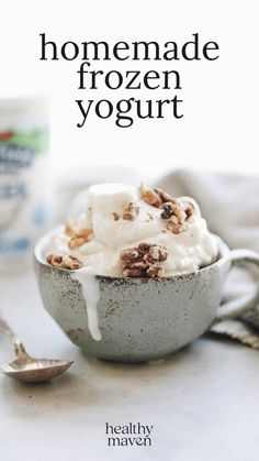 a bowl filled with yogurt and nuts on top of a table next to a spoon