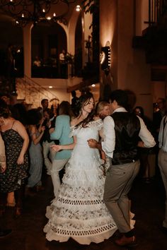 a bride and groom are dancing together in the middle of a room full of people