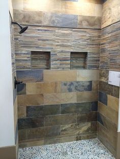 a walk in shower sitting next to a tiled wall and floor covered in brown tiles