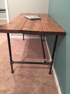 a laptop computer sitting on top of a wooden table in the corner of a room