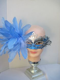 * The silver and turquoise blue mask base has been accented by scrolls of silver glitter and overlaid with a high polish silver scroll design with an outline of faceted clear crystals over the upper eye lids. On the right side an array of blue Goose feathers has been coordinated with tucks of white Maribou feathers. * To secure the mask there are blue satin ribbons used to tie in the back of the head. * Upon ordering this is the exact mask you will receive. * A great piece for a Christmas event, Blue Masquerade Mask For Mardi Gras Costume Party, Elegant Blue Masquerade Mask For Parties, Light Blue Masquerade Mask, Blue Masquerade Mask For Carnival Costume Party, Blue Venetian Masquerade Mask For Party, Blue Masquerade Mask For Mardi Gras, Elegant Blue Eye Mask For Masquerade, Blue Masquerade Mask For Mardi Gras Carnival, Blue Venetian Masquerade Mask