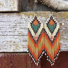 a pair of beaded earrings hanging from a wooden door