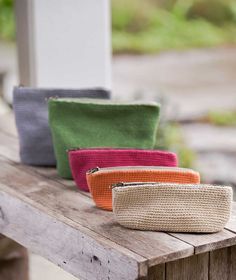 three purses sitting on top of a wooden table next to each other in different colors