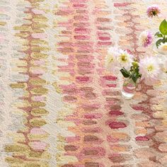 a vase filled with flowers sitting on top of a table next to a wall hanging