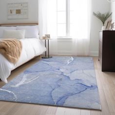 a bedroom with a bed, nightstand and rug on the floor in front of a window