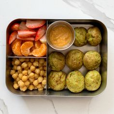 a metal container filled with different types of food and fruit on top of a white table