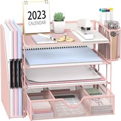 a pink desk with several drawers and a calendar on the top, next to other office supplies