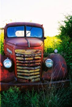 an old rusted truck sitting in the grass