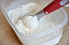 a plastic container filled with ice cream next to a red spatula on top of a table