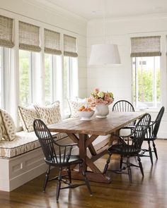 a dining room table with four chairs and a bench in front of the window that is open