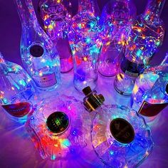 a group of bottles that are sitting on a table with lights in the bottle tops