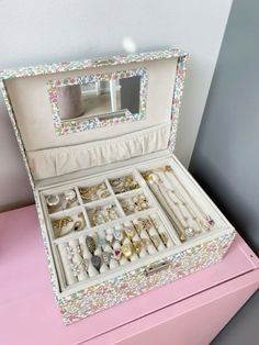 an open jewelry box sitting on top of a pink table