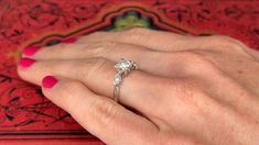 a close up of a person's hand with a diamond ring on their finger