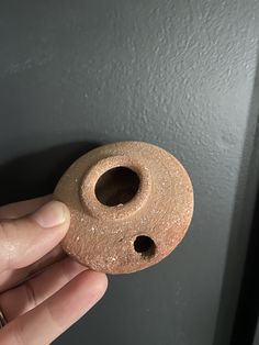 a person is holding an object that looks like a round hole in the side of a wall