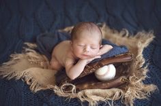 a baby is laying down with a baseball glove and ball