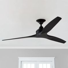 a black ceiling fan mounted to the ceiling in a room with white walls and windows