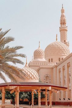 a large white building with many domes on it's sides and palm trees in the foreground