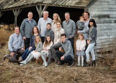 a large group of people posing in front of an old barn