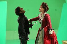 a man and woman dressed in period costumes standing next to each other on a green screen