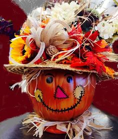 a pumpkin with a hat on top of it sitting on a table next to flowers