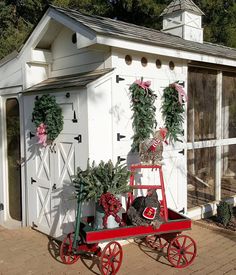 a small white shed with red wagon and christmas decorations