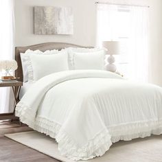 a white bed with ruffled sheets and pillows