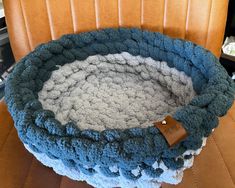 a crocheted basket sitting on top of a brown chair next to a wooden table