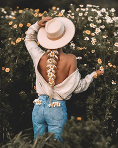 the back of a woman's head with flowers in her hair, wearing jeans and a white hat