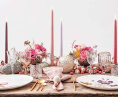 the table is set with pink flowers and candles