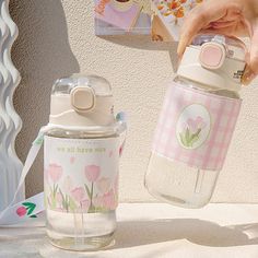 a person is holding a water bottle next to a cup and magazine on a table