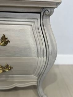 an ornate silver dresser with gold handles and knobs on the drawer pulls is shown in this image