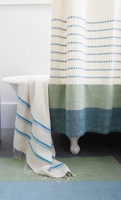 a bath tub sitting next to a blue and green rug on top of a bathroom floor