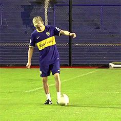 a man kicking a soccer ball on top of a field