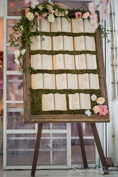 an old book with moss and flowers on it is displayed in front of a window