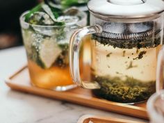 a tea pot filled with green tea next to two glasses