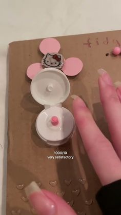 someone is making a hello kitty craft with pink and white decorations on the table top