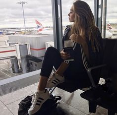 a woman sitting in an airport waiting for her plane to take off and she is looking out the window