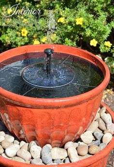 an orange planter filled with rocks and water pouring out of it's center