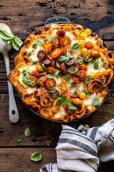 an overhead view of a pasta dish with tomatoes, cheese and basil on the side