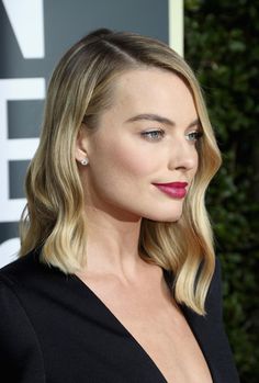 a woman with long blonde hair wearing a black dress and red lipstick at an event