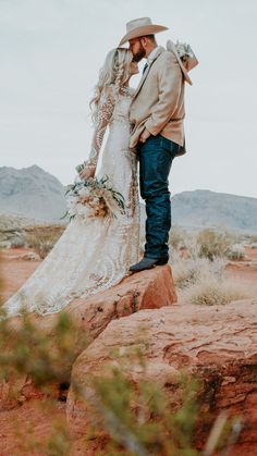 a bride and groom standing on top of a large rock in the middle of nowhere