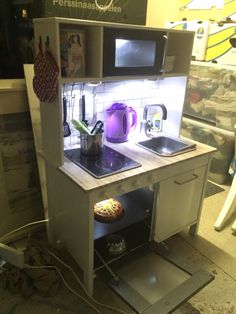 a toy kitchen set up in the shape of a doll house